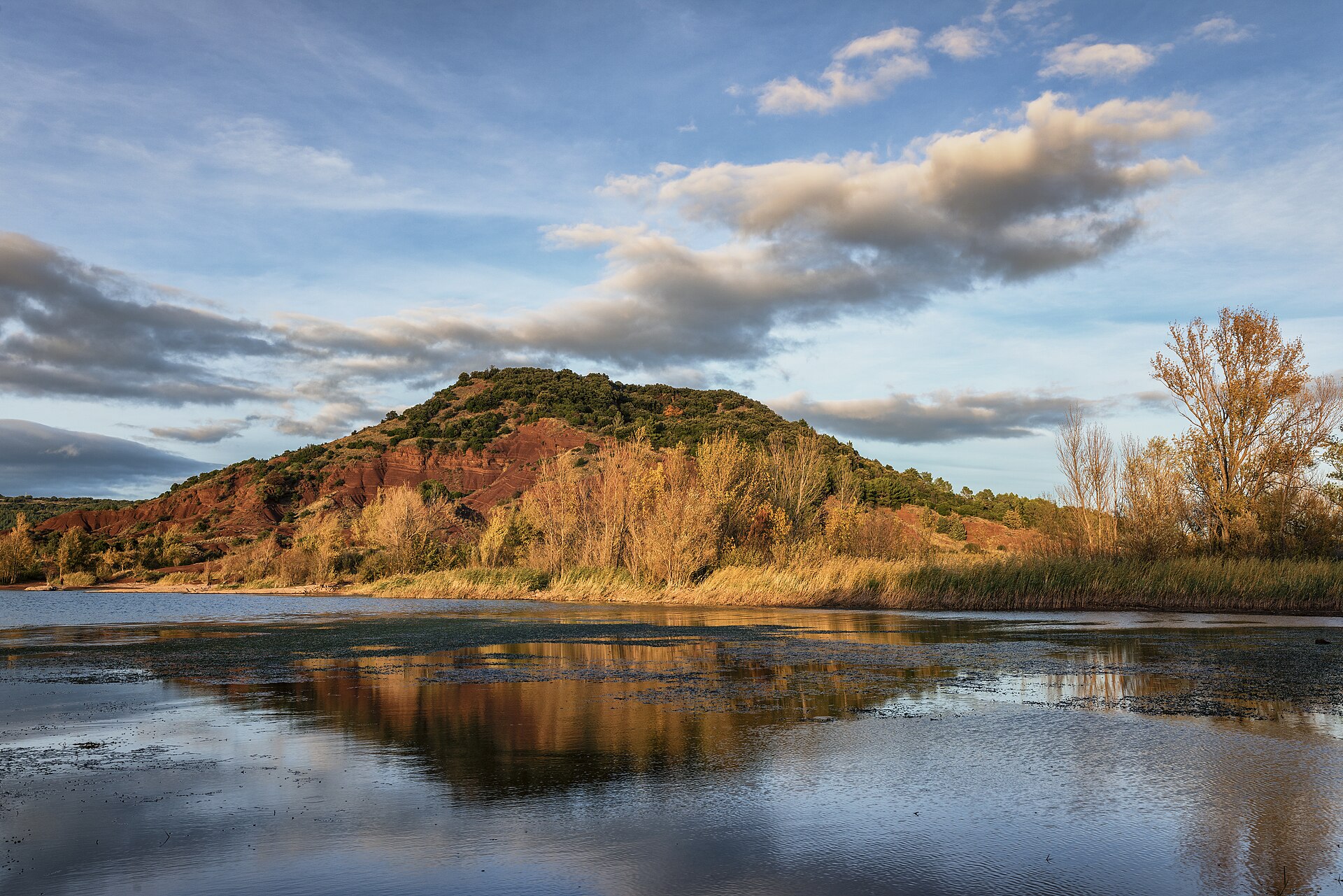 Butte de terre rouge reflétée dans le lac du Salagou